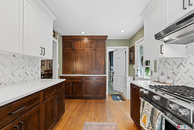 170 Joy Ln, Granville, OH 43023 - kitchen with under cabinet range hood, gas range, decorative backsplash, light countertops, and light wood finished floors