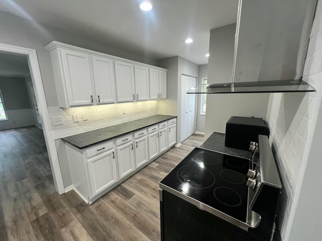 965 Francis Ave, Columbus, OH 43209 - kitchen featuring stove, wall chimney exhaust hood, wood finished floors, decorative backsplash, and dark countertops