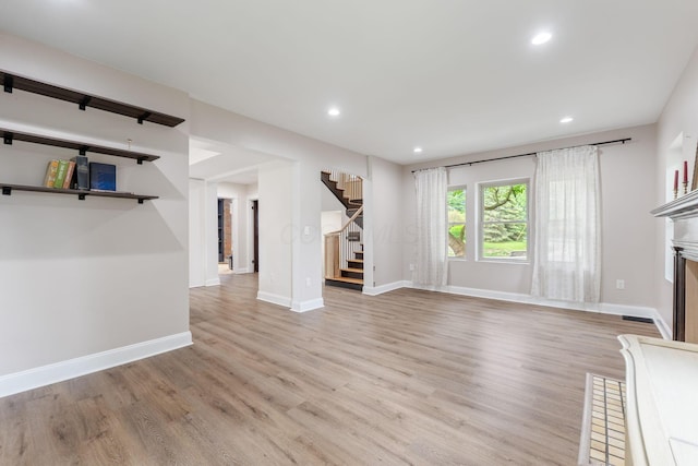 992 N Nelson Rd, Columbus, OH 43219 - unfurnished living room featuring stairway, light wood finished floors, a fireplace, and recessed lighting