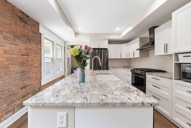992 N Nelson Rd, Columbus, OH 43219 - kitchen with wall chimney range hood, gas stove, freestanding refrigerator, brick wall, and dark wood finished floors
