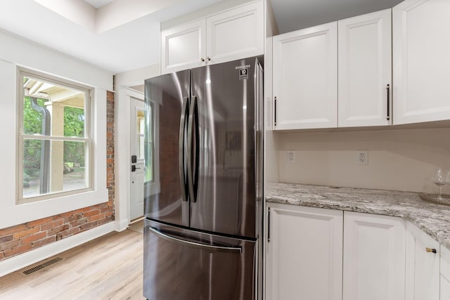 992 N Nelson Rd, Columbus, OH 43219 - kitchen with freestanding refrigerator, white cabinets, brick wall, light stone countertops, and light wood-style floors