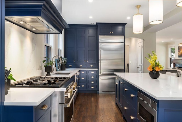 249 E Whittier St, Columbus, OH 43206 - kitchen featuring built in appliances, blue cabinets, custom exhaust hood, dark wood finished floors, and recessed lighting