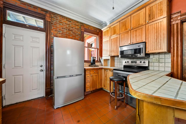 726 Franklin Ave, Columbus, OH 43205 - kitchen featuring stainless steel appliances, tile countertops, dark tile patterned flooring, tasteful backsplash, and crown molding