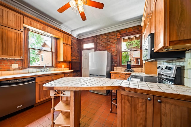 726 Franklin Ave, Columbus, OH 43205 - kitchen featuring stainless steel appliances, tile countertops, dark tile patterned floors, brown cabinetry, and ornamental molding