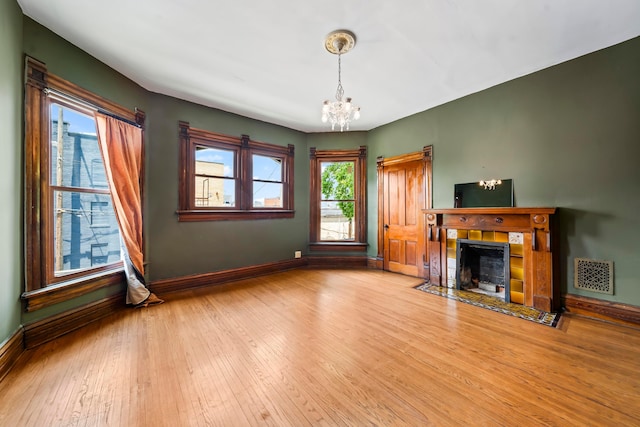 726 Franklin Ave, Columbus, OH 43205 - unfurnished living room with a chandelier, hardwood / wood-style floors, and a tiled fireplace