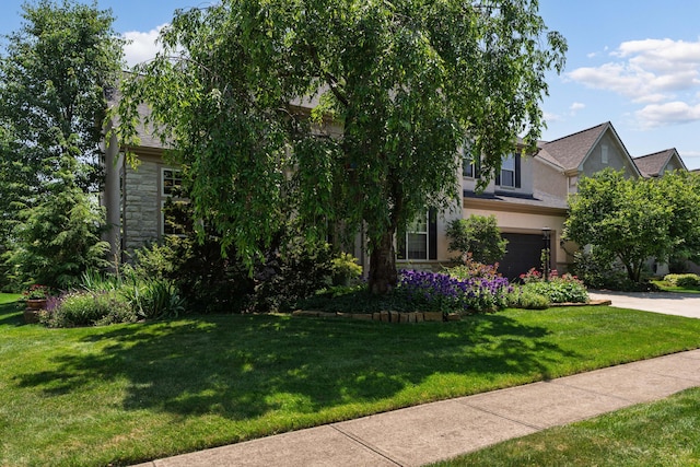 5650 Tynecastle Loop, Dublin, OH 43016 - obstructed view of property with an attached garage, stone siding, stucco siding, concrete driveway, and a front lawn