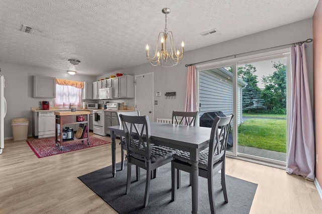 7780 Freesia St Unit 228, Blacklick, OH 43004 - dining space featuring light wood finished floors, a chandelier, healthy amount of natural light, and a textured ceiling