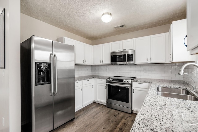 5595 Marshfield Dr, Westerville, OH 43081 - kitchen with appliances with stainless steel finishes, dark wood-style floors, white cabinetry, decorative backsplash, and light stone countertops