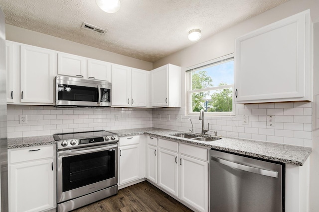5595 Marshfield Dr, Westerville, OH 43081 - kitchen featuring stainless steel appliances, dark wood-style flooring, white cabinets, light stone counters, and a textured ceiling