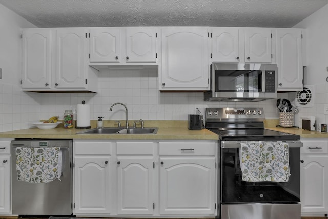 5252 Roche Pl, Columbus, OH 43229 - kitchen with appliances with stainless steel finishes, white cabinets, light countertops, decorative backsplash, and a textured ceiling