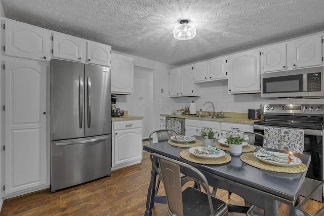 5252 Roche Pl, Columbus, OH 43229 - kitchen with stainless steel appliances, white cabinets, dark wood-style floors, a textured ceiling, and light countertops