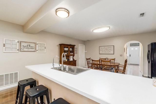 4867 Fosterson Dr, Lockbourne, OH 43137 - kitchen with freestanding refrigerator, light wood-style floors, a breakfast bar, arched walkways, and light countertops