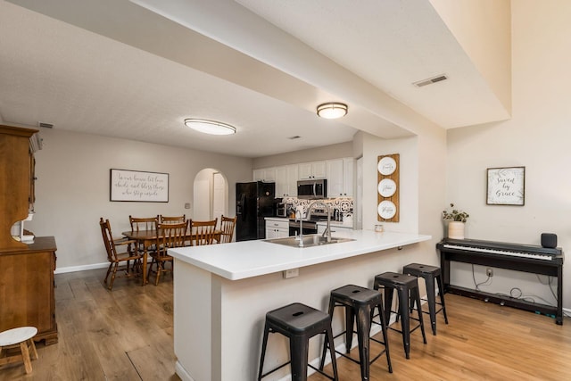 4867 Fosterson Dr, Lockbourne, OH 43137 - kitchen with stainless steel appliances, arched walkways, a peninsula, light wood-type flooring, and a breakfast bar area