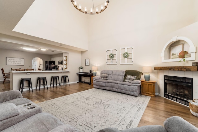 4867 Fosterson Dr, Lockbourne, OH 43137 - living area featuring wood finished floors, a chandelier, a tile fireplace, and arched walkways