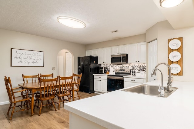 4867 Fosterson Dr, Lockbourne, OH 43137 - kitchen with appliances with stainless steel finishes, arched walkways, light wood-style floors, white cabinets, and backsplash