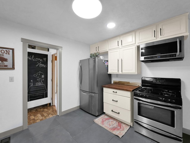 800 Spring Rd S, Westerville, OH 43081 - kitchen with appliances with stainless steel finishes, butcher block counters, dark tile patterned floors, white cabinets, and recessed lighting