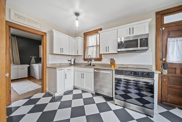 94 W Waterloo St, Canal Winchester, OH 43110 - kitchen with stainless steel appliances, dark flooring, washing machine and clothes dryer, and white cabinetry