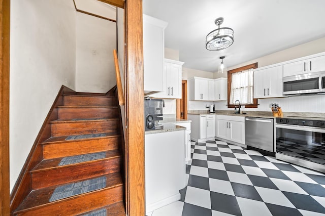 94 W Waterloo St, Canal Winchester, OH 43110 - kitchen featuring appliances with stainless steel finishes, dark floors, white cabinets, light stone countertops, and decorative light fixtures