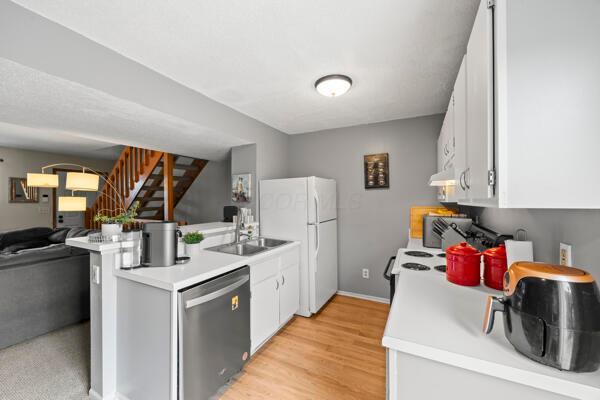 5153 Singleton Dr Unit 44B, Hilliard, OH 43026 - kitchen featuring dishwasher, freestanding refrigerator, a peninsula, white cabinetry, and light countertops