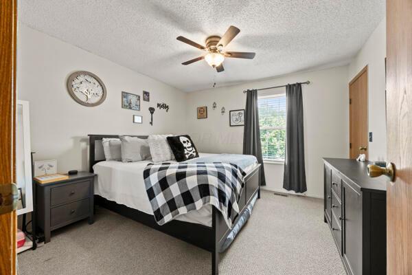 5153 Singleton Dr Unit 44B, Hilliard, OH 43026 - bedroom featuring light colored carpet, a textured ceiling, and a ceiling fan