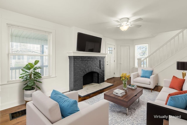 786 Ann St, Columbus, OH 43206 - living room with wood finished floors, a ceiling fan, a brick fireplace, and stairway