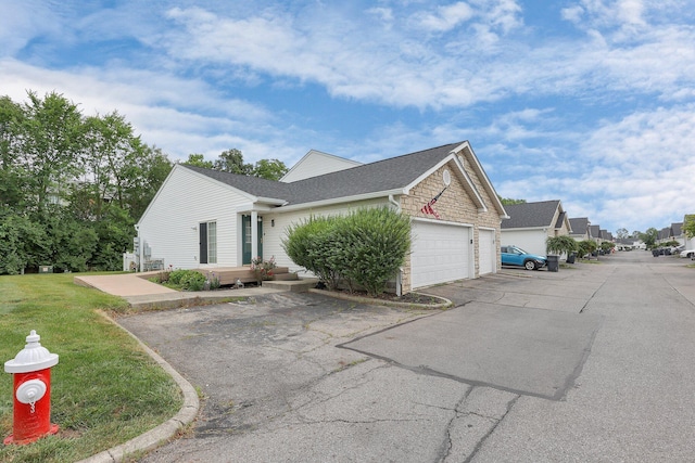 4686 Parrau Dr Unit 64A, Columbus, OH 43228 - view of home's exterior featuring a garage, asphalt driveway, a shingled roof, a yard, and stone siding