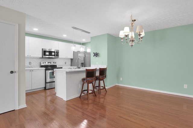 4686 Parrau Dr Unit 64A, Columbus, OH 43228 - kitchen featuring appliances with stainless steel finishes, dark wood finished floors, tasteful backsplash, a kitchen breakfast bar, and white cabinets
