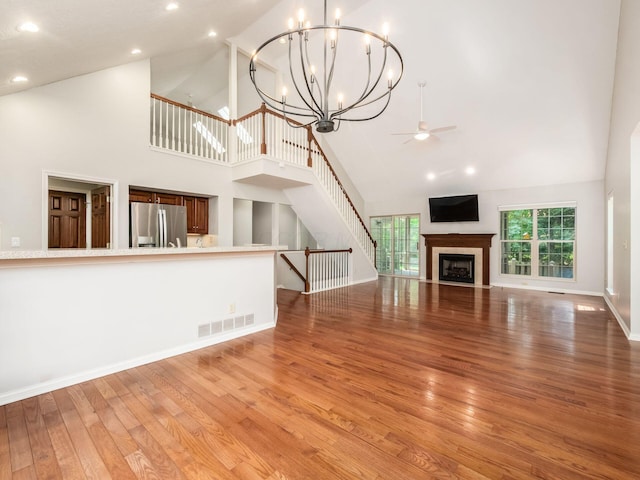 6003 Dunabbey Loop, Dublin, OH 43017 - unfurnished living room with high vaulted ceiling, light wood-style flooring, a ceiling fan, a fireplace, and stairs