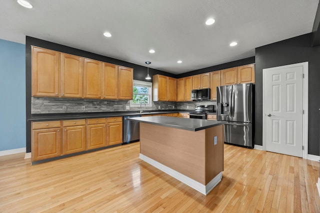 4003 Laurel Valley Dr, Powell, OH 43065 - kitchen featuring appliances with stainless steel finishes, dark countertops, decorative backsplash, light wood finished floors, and a kitchen island