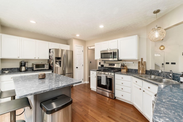 7954 Windrift Pl, Reynoldsburg, OH 43068 - kitchen featuring appliances with stainless steel finishes, a breakfast bar area, white cabinets, dark wood-style flooring, and a textured ceiling