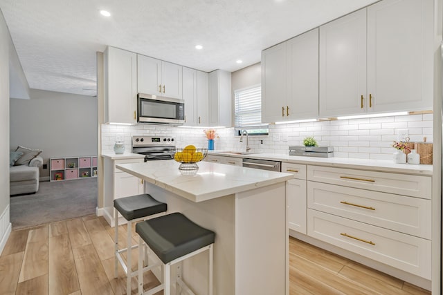 1439 Tall Meadows Dr, Columbus, OH 43223 - kitchen featuring stainless steel appliances, light wood-type flooring, a center island, white cabinets, and recessed lighting