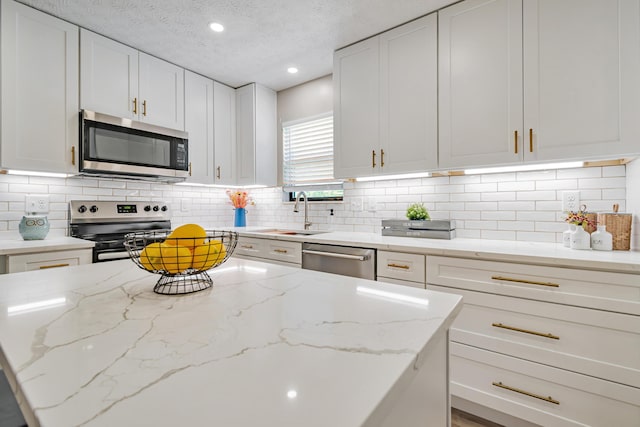 1439 Tall Meadows Dr, Columbus, OH 43223 - kitchen with stainless steel appliances, white cabinets, decorative backsplash, light stone countertops, and a textured ceiling