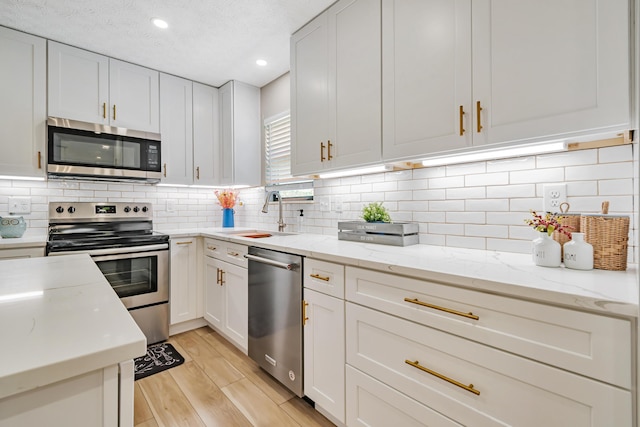 1439 Tall Meadows Dr, Columbus, OH 43223 - kitchen with stainless steel appliances, light wood-style floors, recessed lighting, white cabinetry, and tasteful backsplash