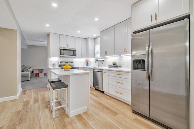 1439 Tall Meadows Dr, Columbus, OH 43223 - kitchen featuring stainless steel appliances, light countertops, backsplash, light wood finished floors, and a kitchen island