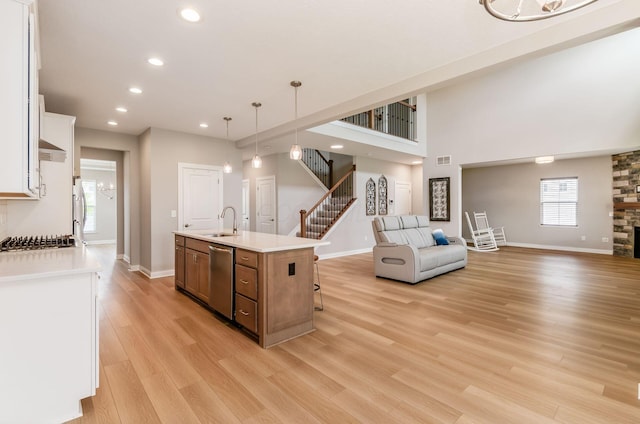 600 Courtright Dr E, Pickerington, OH 43147 - kitchen featuring appliances with stainless steel finishes, open floor plan, an island with sink, light wood-style floors, and white cabinetry