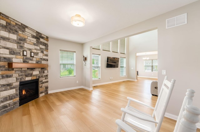600 Courtright Dr E, Pickerington, OH 43147 - unfurnished living room featuring a stone fireplace, light wood finished floors, plenty of natural light, and a chandelier