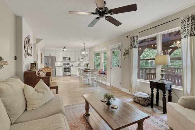 437 Barrington Rdg, Pataskala, OH 43062 - living room with light wood-style floors, ceiling fan, a chandelier, and a textured ceiling