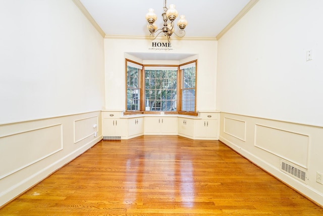 670 Greenwich St, Worthington, OH 43085 - unfurnished room featuring a chandelier, ornamental molding, wainscoting, light wood-style floors, and a decorative wall