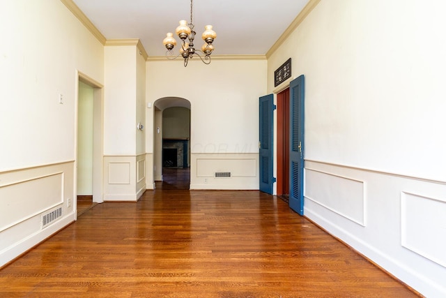 670 Greenwich St, Worthington, OH 43085 - spare room featuring arched walkways, ornamental molding, a chandelier, wood finished floors, and a decorative wall