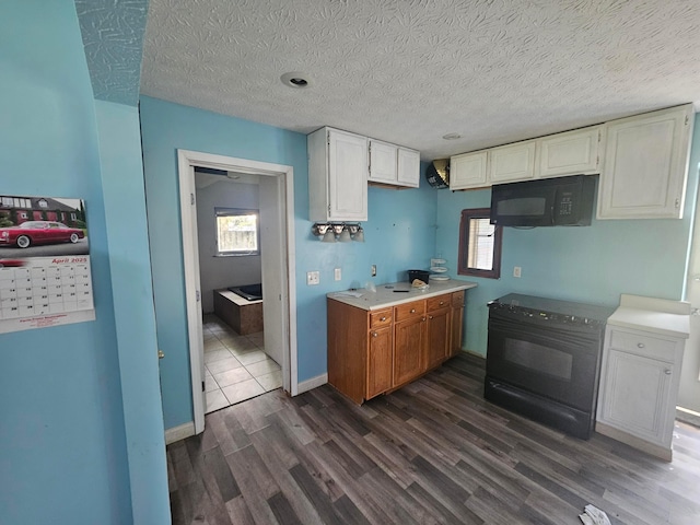 710 Glendower Ave, Columbus, OH 43207 - kitchen featuring black appliances, dark wood-type flooring, light countertops, white cabinets, and a textured ceiling