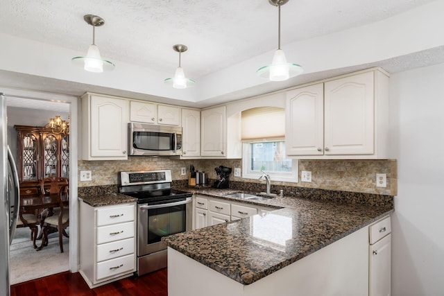 2740 Mitzi Dr, Columbus, OH 43209 - kitchen featuring appliances with stainless steel finishes, dark wood-style flooring, a textured ceiling, a peninsula, and decorative backsplash