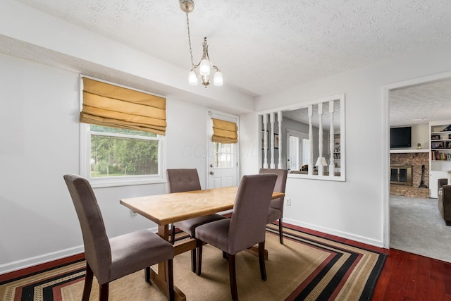 2740 Mitzi Dr, Columbus, OH 43209 - dining room featuring a textured ceiling, wood finished floors, a chandelier, and a glass covered fireplace