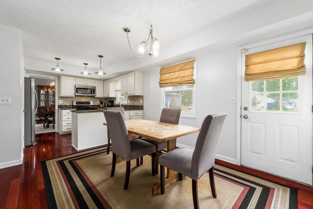 2740 Mitzi Dr, Columbus, OH 43209 - dining area with dark wood finished floors, a textured ceiling, and a chandelier