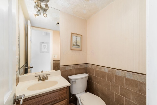 2740 Mitzi Dr, Columbus, OH 43209 - half bathroom with vanity, a wainscoted wall, a textured ceiling, and tile walls