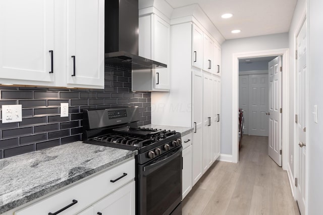 6704 Blacks Rd SW, Pataskala, OH 43062 - kitchen with black gas range oven, wall chimney exhaust hood, white cabinetry, light wood-type flooring, and decorative backsplash