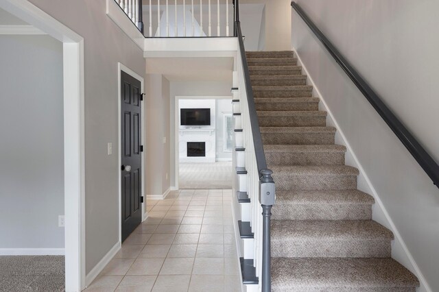 833 Moon Glow Ct, Columbus, OH 43230 - staircase with tile patterned flooring, a fireplace, carpet floors, and a high ceiling