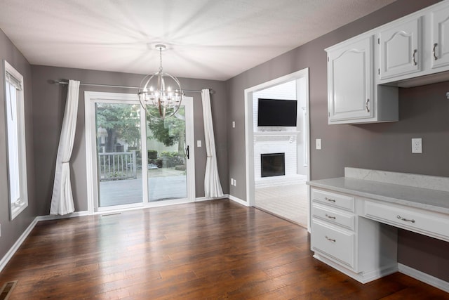 833 Moon Glow Ct, Columbus, OH 43230 - kitchen featuring a chandelier, dark wood-style floors, white cabinets, pendant lighting, and a fireplace