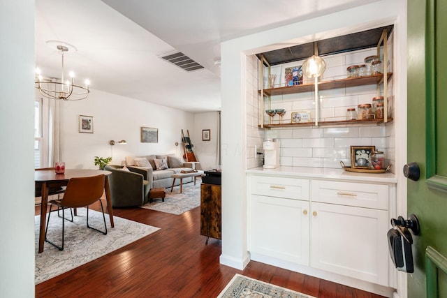 249 E Kossuth St Unit E, Columbus, OH 43206 - bar featuring tasteful backsplash, dark wood-style floors, a chandelier, and decorative light fixtures