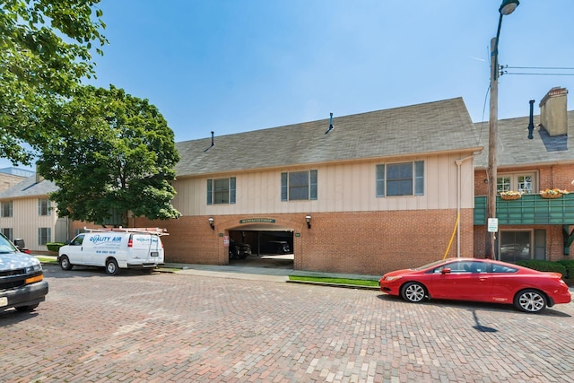 249 E Kossuth St Unit E, Columbus, OH 43206 - view of front of house featuring brick siding, a shingled roof, uncovered parking, and board and batten siding