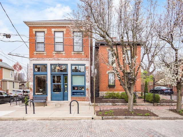 249 E Kossuth St Unit E, Columbus, OH 43206 - townhome / multi-family property featuring brick siding, a fenced front yard, and entry steps